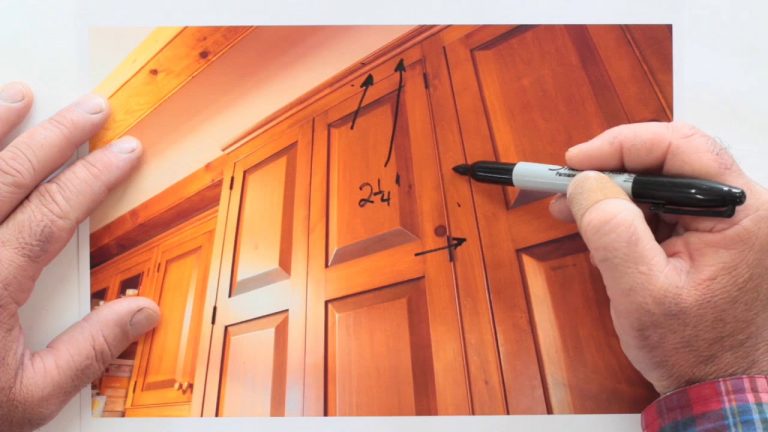 Measuring and marking dimensions on wooden cabinets.