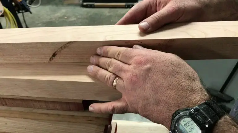 Hands measuring wooden board for carpentry.