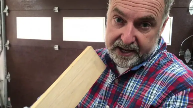 Person holding wooden plank in workshop.