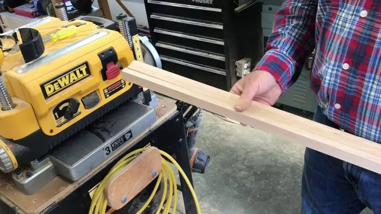Person using wood planer in workshop.