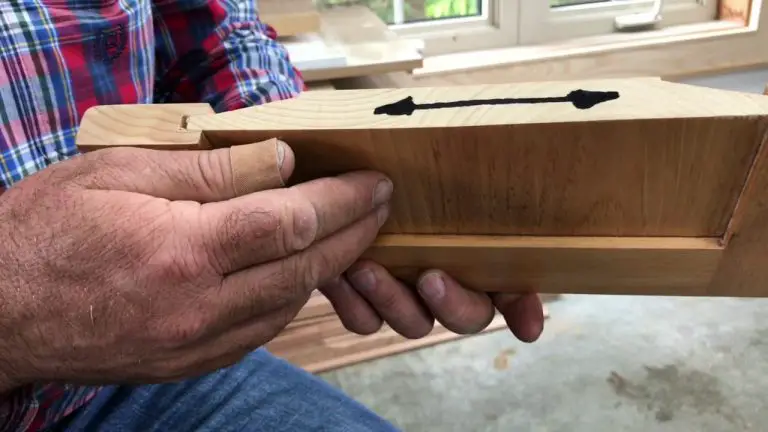 Hands holding wooden piece with arrow marking
