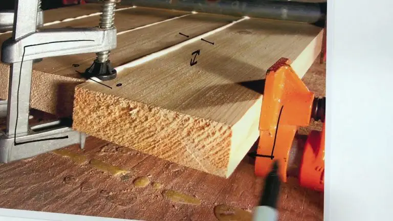 Wood plank clamped on workbench for cutting.