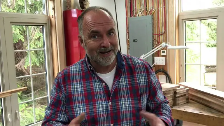 Man in plaid shirt inside woodworking shop.
