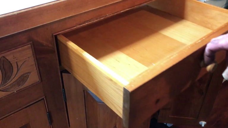 Open wooden drawer with floral carving detail.