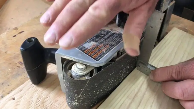 Hand adjusting biscuit joiner on wood surface.
