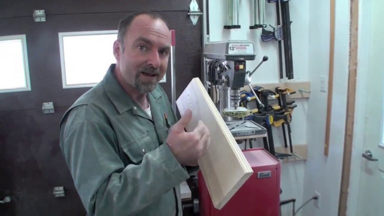 Man showing wooden board in workshop.