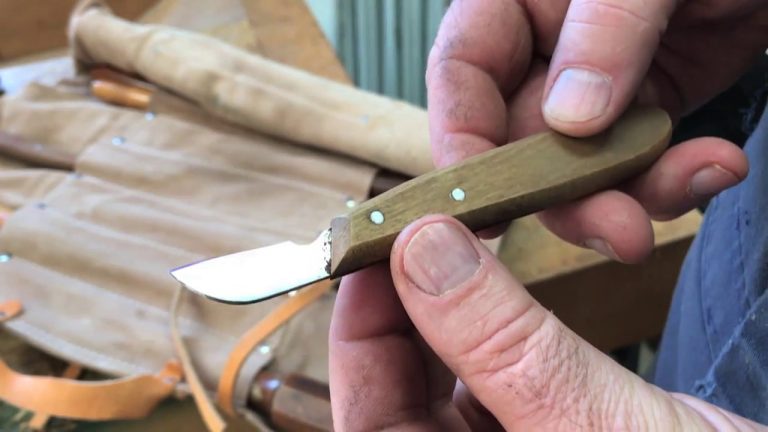 Hand holds a small wood-handled carving knife.
