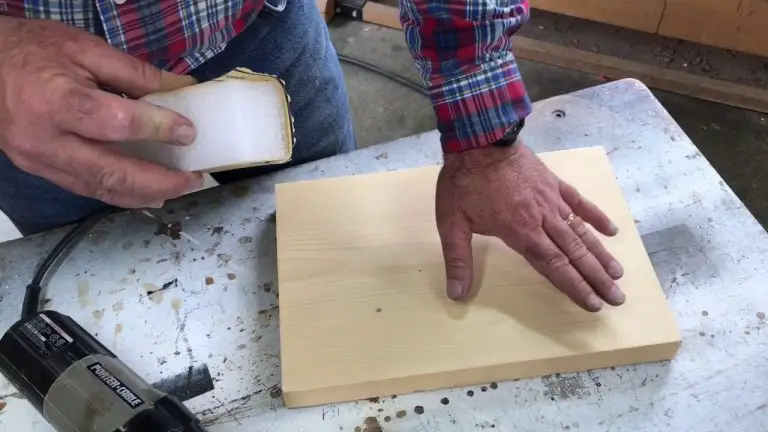 Sanding a wooden board on workbench.