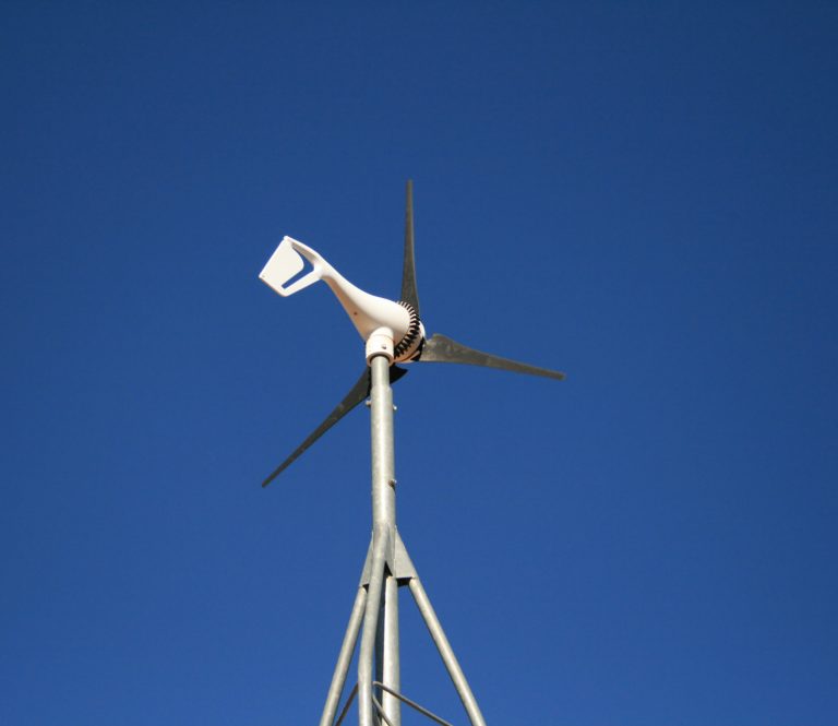 Small wind turbine against clear blue sky.