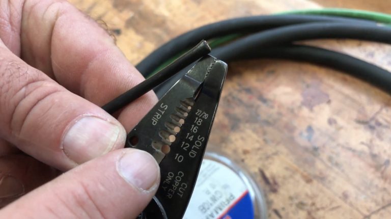 Using wire stripper on black electrical cable.