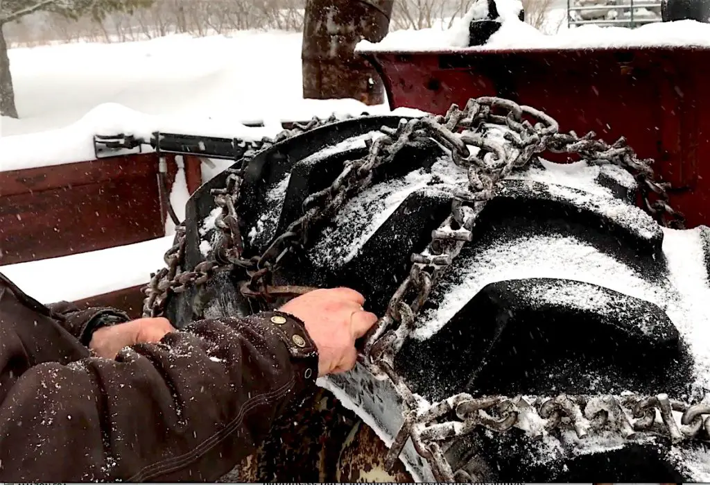 Installing snow chains on tractor tire in winter
