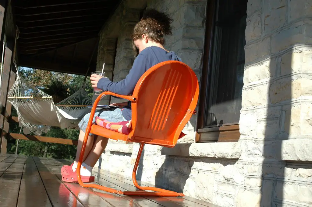 Child sitting outside on patio with a drink.