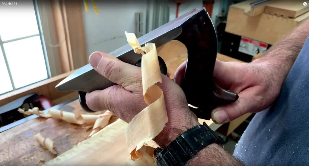 Woodworker using hand plane for precise woodworking.
