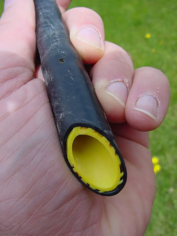 Trickle line sliced where an emitter is. Note the passages around the outside of the emitter where water passes through before dripping out the hole.
