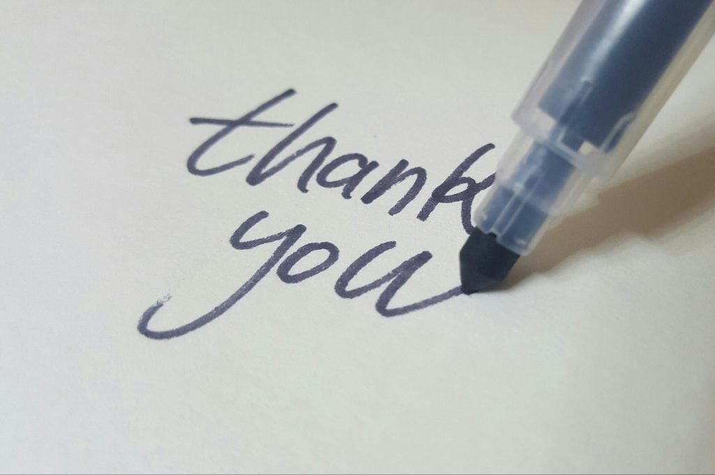 Pen writing 'thank you' on paper