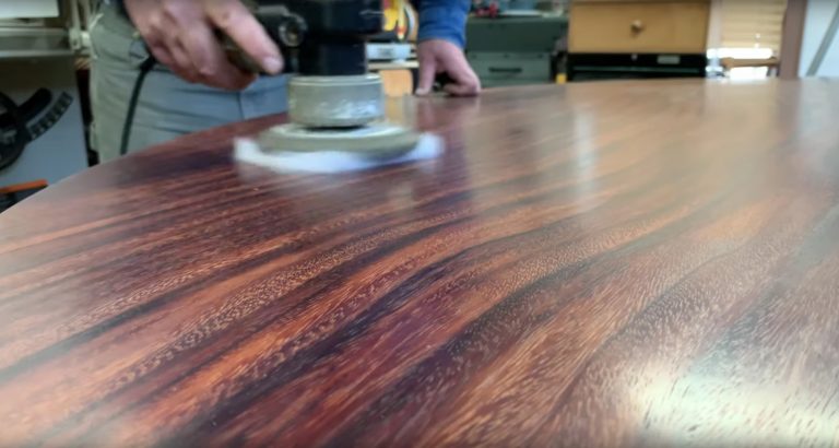 Sanding wood table, creating smooth surface.