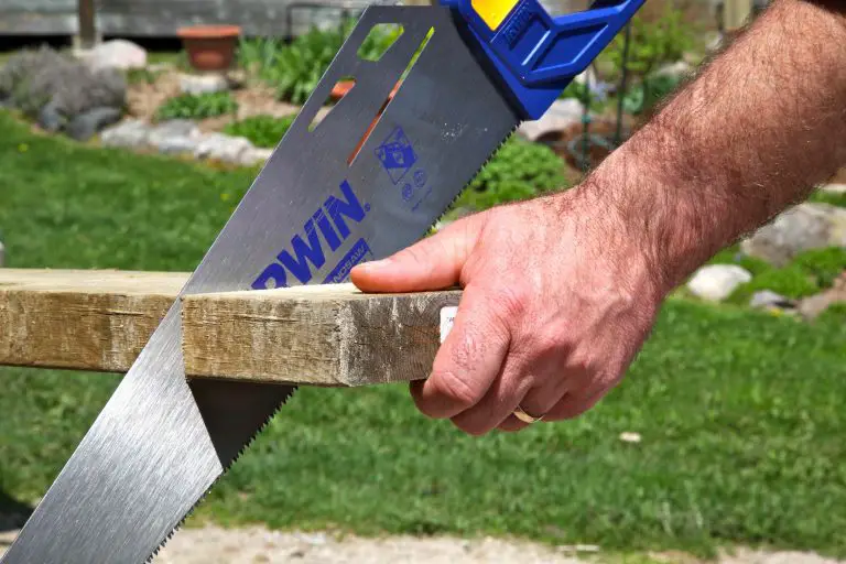 Person sawing wood in backyard.