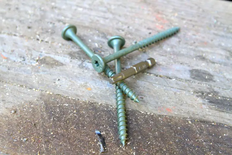 Green screws and bit on wooden surface.