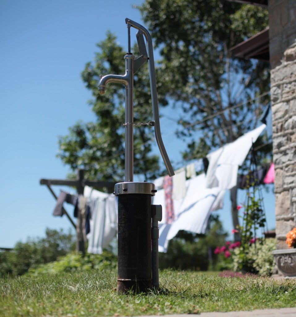 Outdoor hand water pump near clothing line.