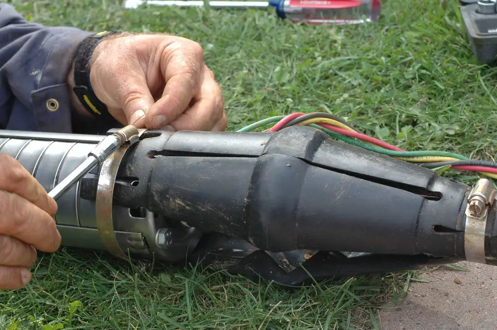 Person repairing electrical cable connection outdoors.