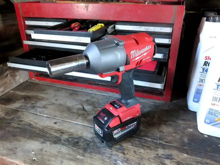 Red cordless impact wrench in workshop setting.