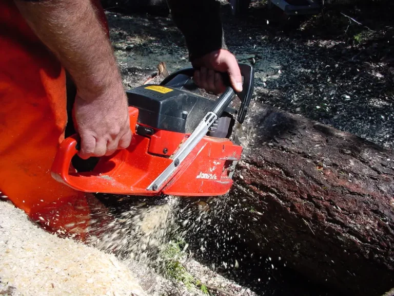 Person cutting wood with a chainsaw outdoors.