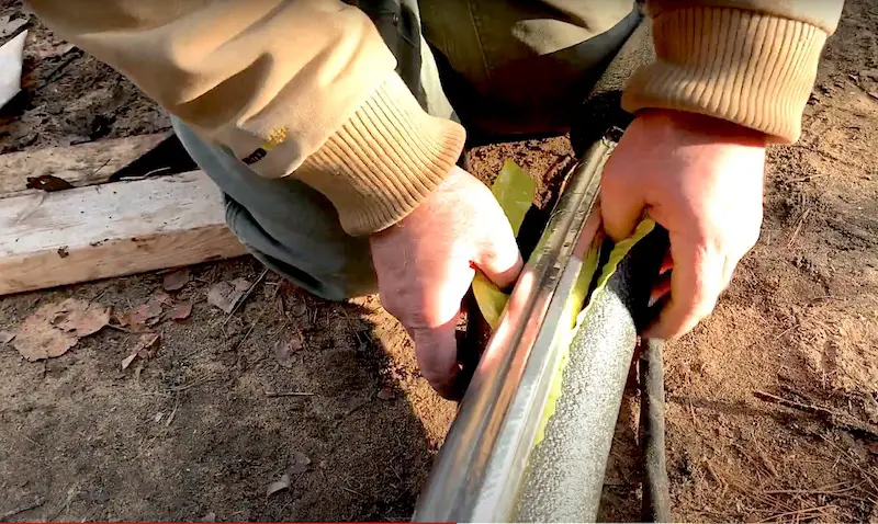 Person sharpening a blade on a grindstone outdoors.