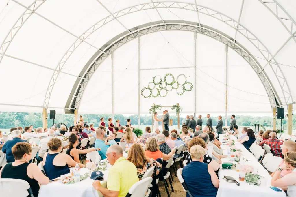 Outdoor wedding ceremony in decorated tent.