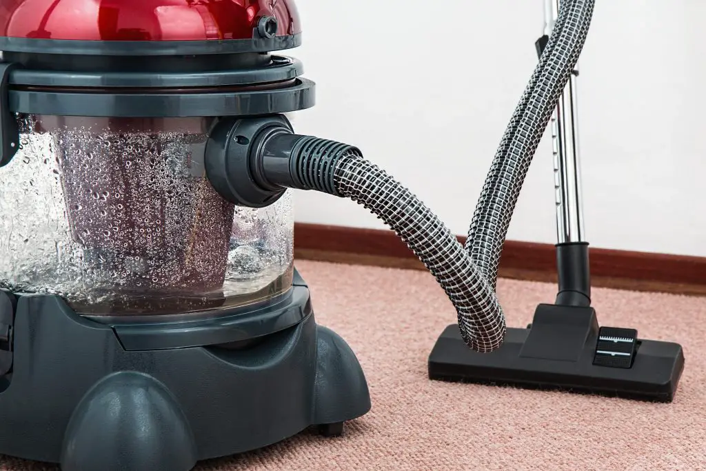 Red vacuum cleaner on carpet floor.