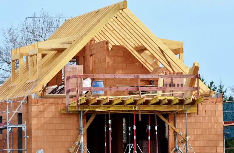 Wooden roof trusses on unfinished brick house construction.
