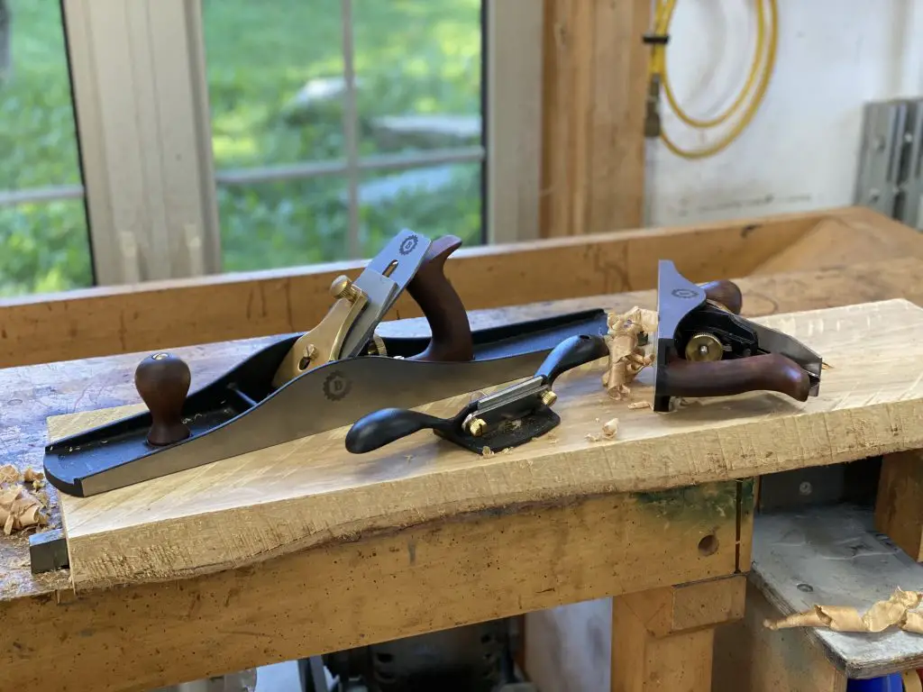 Woodworking plane tools on workbench near window.