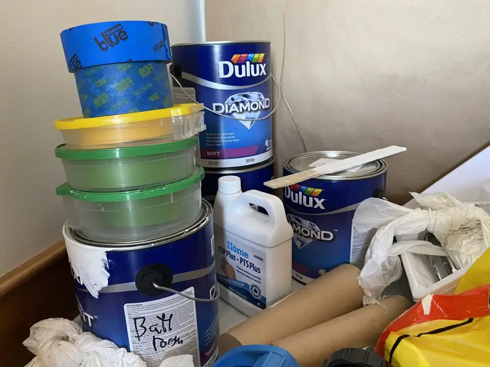 Painting supplies and stacked containers on a table.