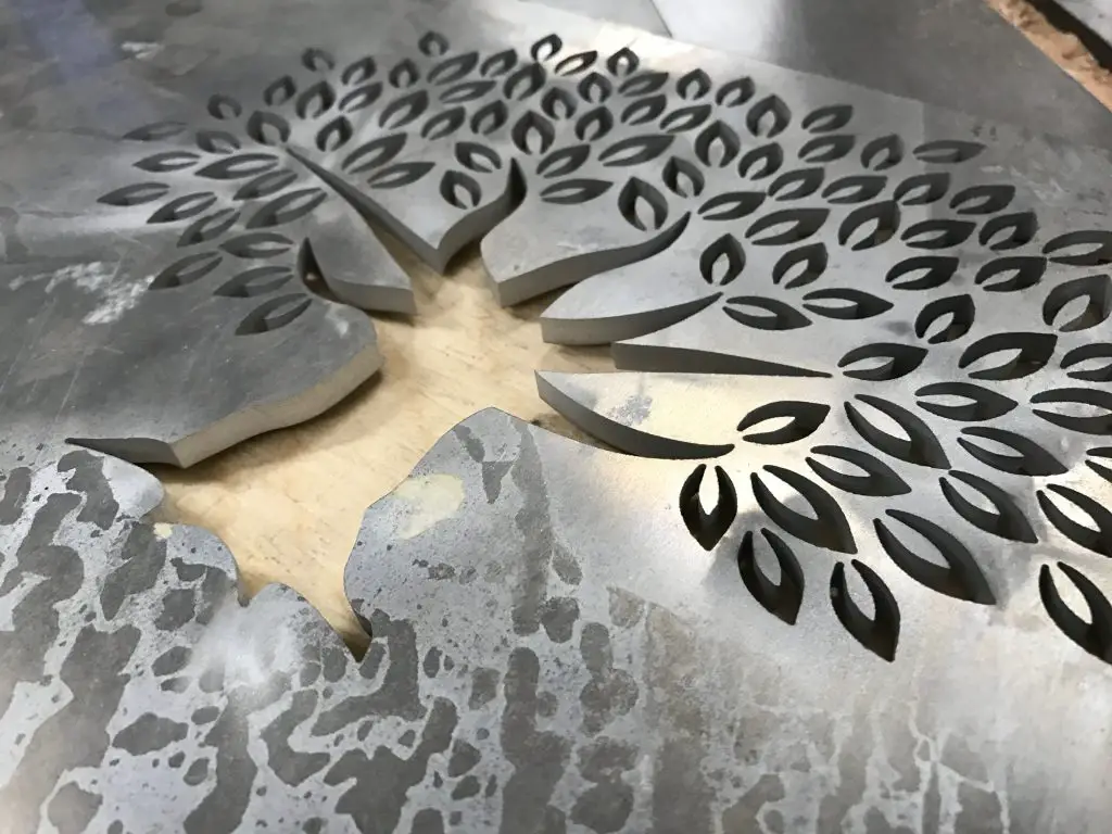 Intricate maple leaf design cut into steel sheet.