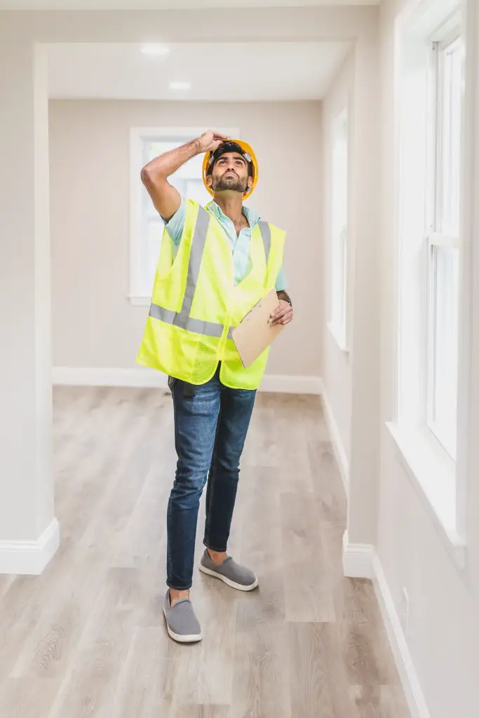 Home inspector examining ceiling with clipboard