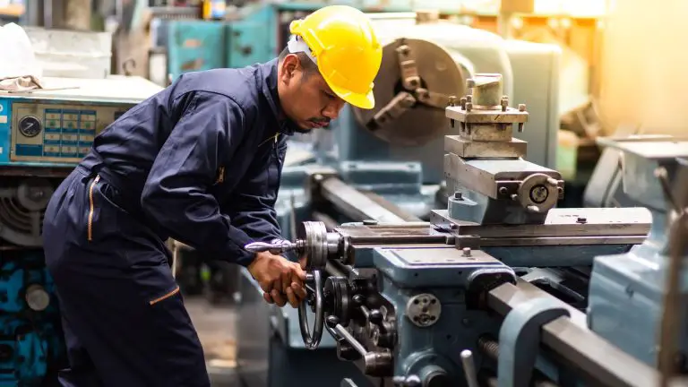 Worker operating industrial metal lathe machine.