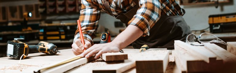 Carpenter measuring wood with tools on workbench.