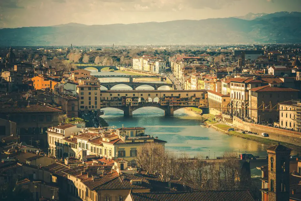 Aerial panoramic view of Florence, Italy with historic architecture river bridges and Monte Morello in background.