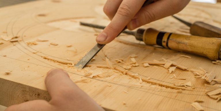 Hand carving wood with chisel.