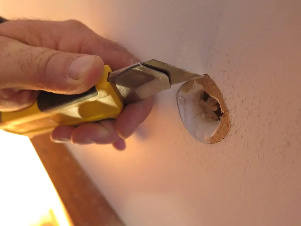 Here I am trimming away frazzled paper from around a hole I’m patching in drywall. This is a key step to patching walls properly.