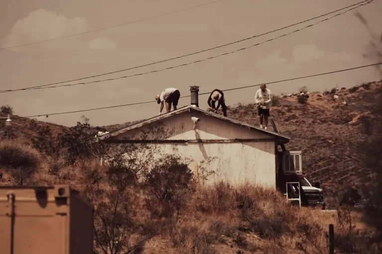 Workers fixing roof in desert landscape