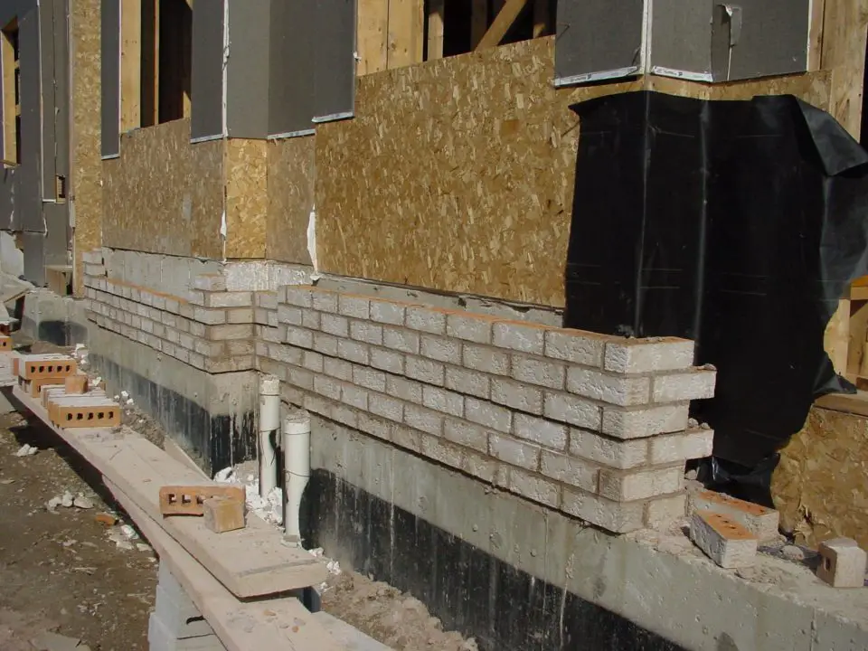 Brick veneer being installed on a wood frame house in Canada. Brick used in this way allows the durability of masonry to combine with the energy efficiency of a wood frame house.