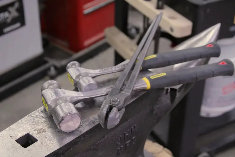 Two ball peen hammers and a pair of tongs sitting on my anvil. Tongs like these are made to grip a specific thickness of metal.