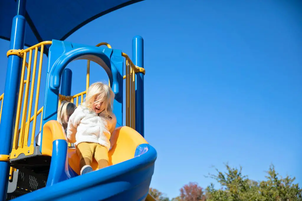 Child sliding down colourful playground slide