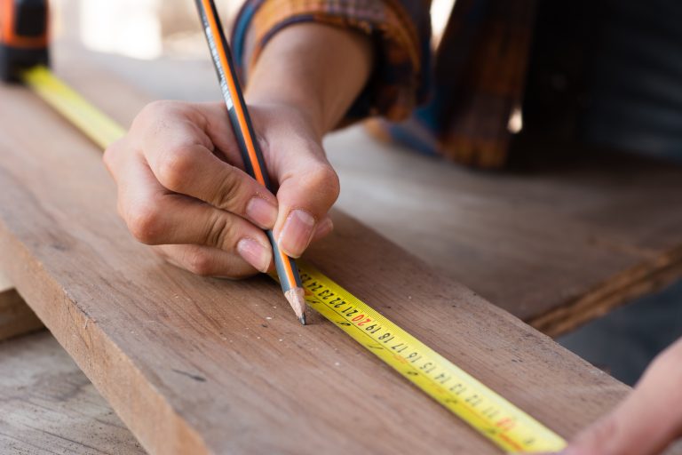 Measuring wood with pencil and tape measure.