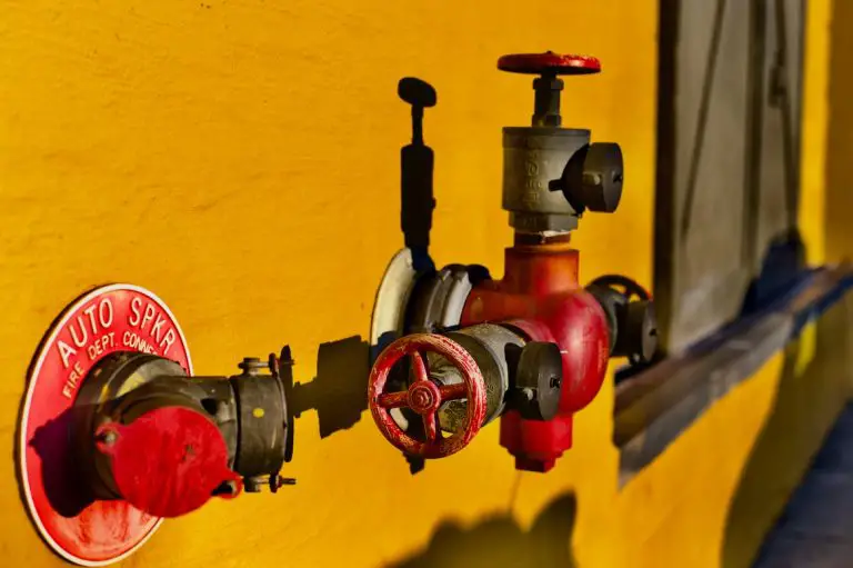 Red fire department connection on yellow wall