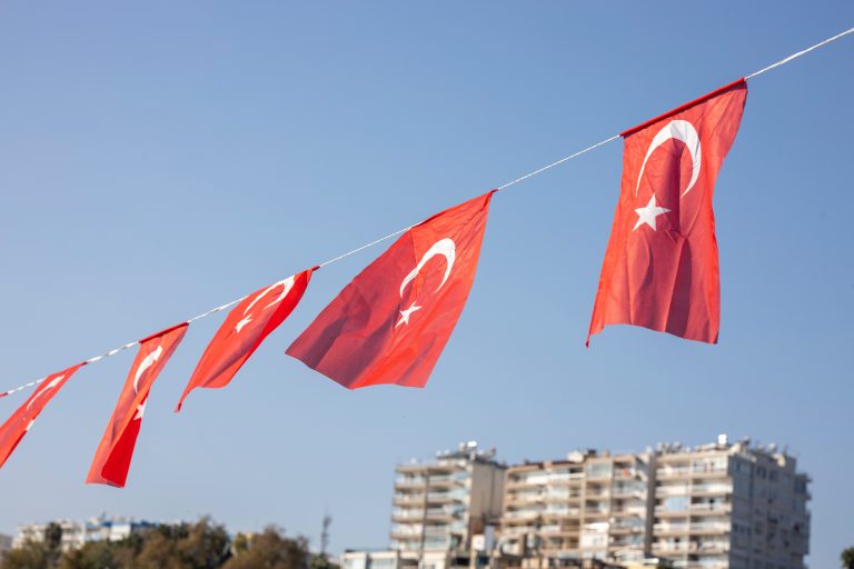 Turkish flags waving in city skyline.