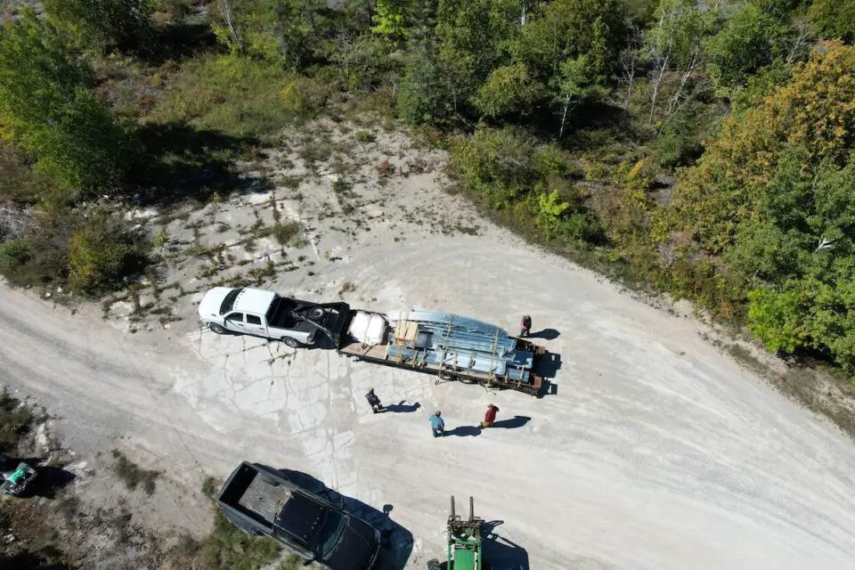 Aerial view of trucks on dirt road with trees.