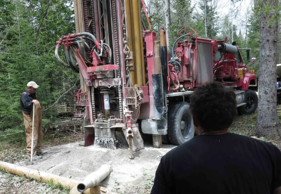 Men operating a large drilling machine in forest