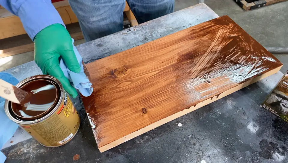 Applying wood stain on a wooden board.