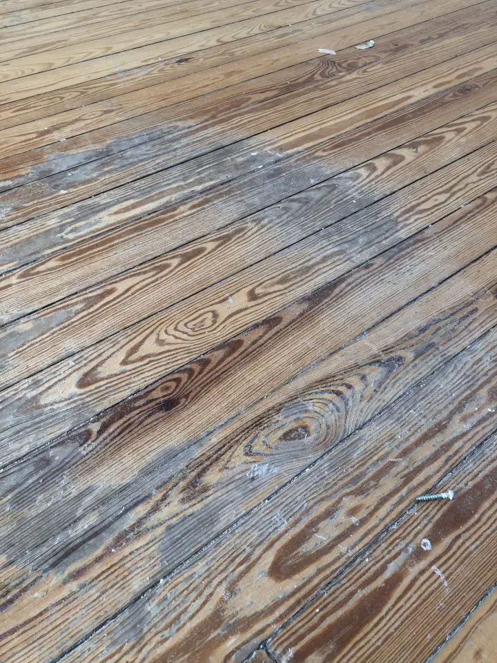 Grey staining and wear like this is common on old, worn wooden floors. This is the same floor that looks so much better refinished in other parts of this article.